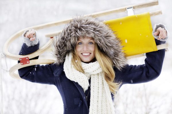 Junge Frau im blauen Wintermantel mit Schlitten  Young Woman with Sleigh Wearing a Blue Winter Coat