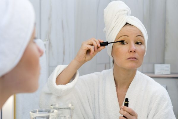 Junge Frau im Badezimmer verwendet Wimperntusche - young woman in bath takes mascara