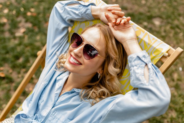 attractive-blond-smiling-woman-sitting-relaxed-deck-chair-stylish-outfit_285396-8242